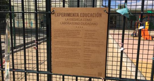 Foto de la valla de un colegio con cartel en madera de Experimenta Educación